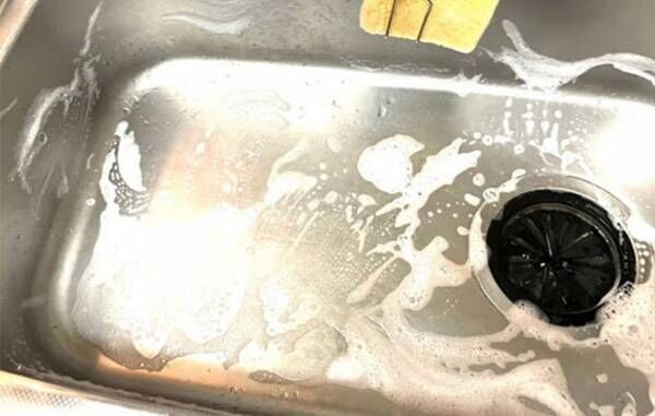 スポンジで洗い泡だらけになったキッチンシンクの写真