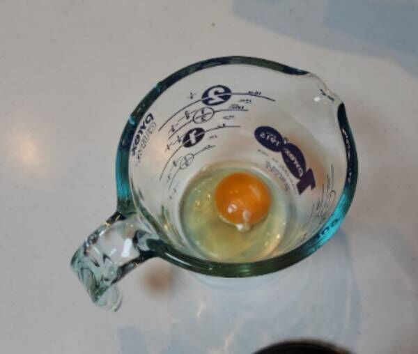 計量カップの中に入れられた生卵