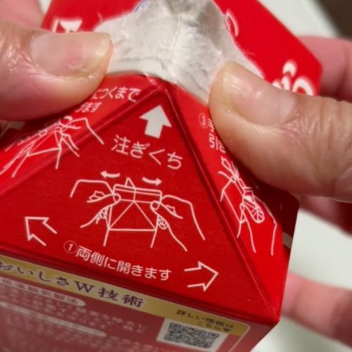 牛乳パックの開け口を押し広げている様子