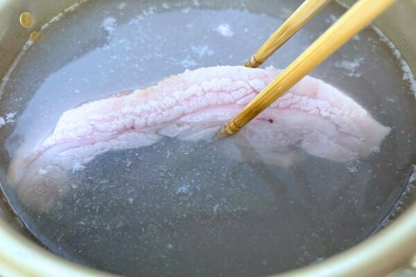 豚肉のかたまりを鍋に入れる様子