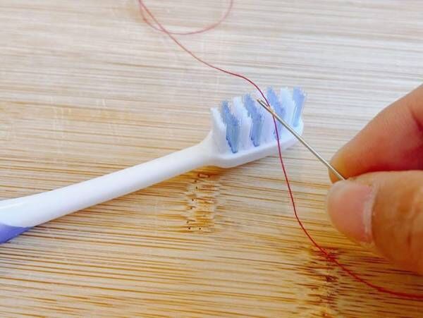歯ブラシで糸とおしをする写真