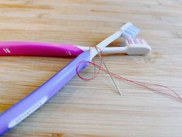 歯ブラシで糸とおしをする写真