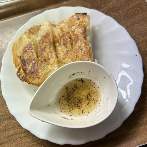 皿の上に盛り付けられた餃子と小皿に入ったレモンコショウ