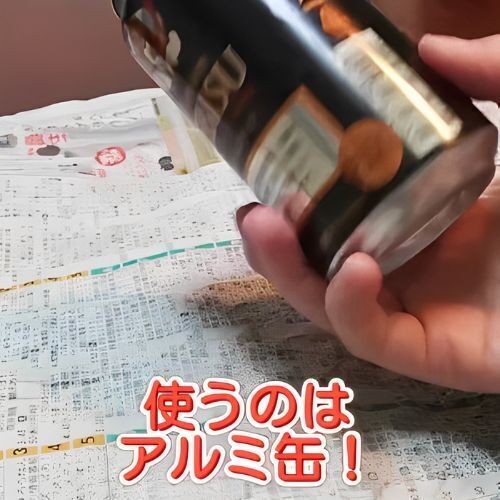 新聞紙の上でアルミ缶を持っている様子