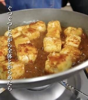 焼いた豆腐に調味料を絡める様子