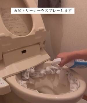 便器裏に詰めたトイレットペーパーにトイレ掃除用の洗剤を吹きかける様子