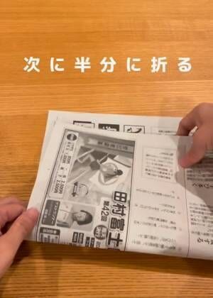 ２枚の新聞紙をそのまま重ねて、縦長になるように置いたら、さらに半分に折りましょう。