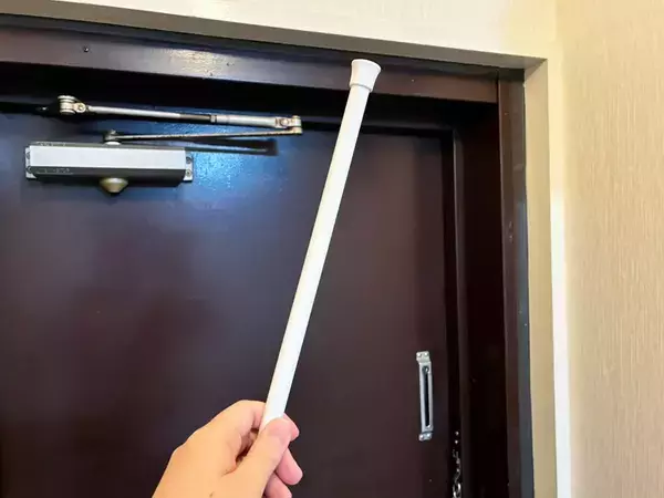 玄関ドア枠の上に『つっぱり棒』を設置するとスッキリ　狭い空間の収納力をアップさせる活用法
