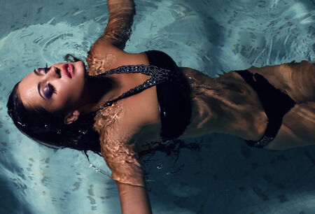 31180586 - fashion photo of sexy beautiful girl with dark hair posing in swimming pool at night