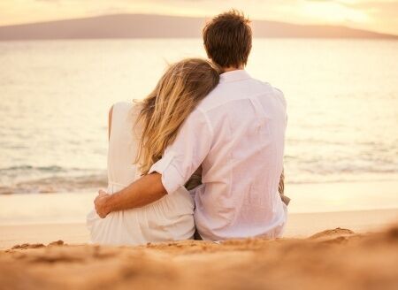 24227808 - young couple in love, attractive man and woman enjoying romantic evening on the beach watching the sunset