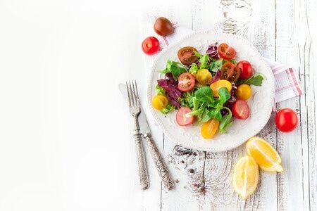 38444478 - fresh salad with cherry tomatoes, spinach, arugula, romaine and lettuce in a plate on white wooden background, top view