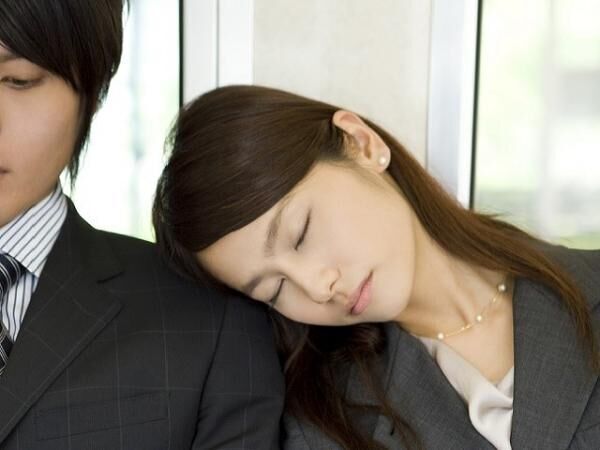 Business woman having a nap while sitting on seat of train