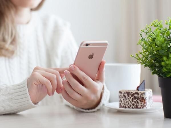 Woman holding iPhone 6 S Rose Gold in cafe