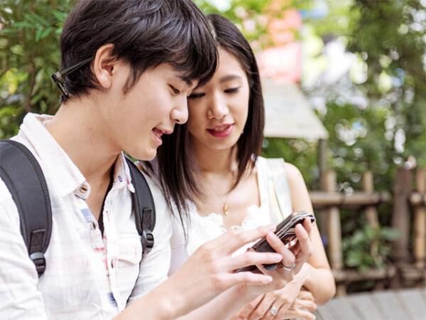 Young Japanese couple using mobile phone