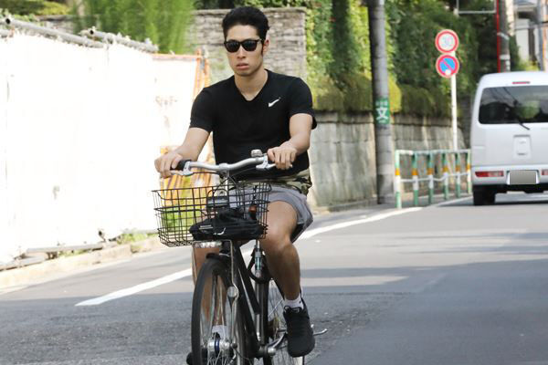 閑静な住宅街を自転車に乗って走り去る萩野。