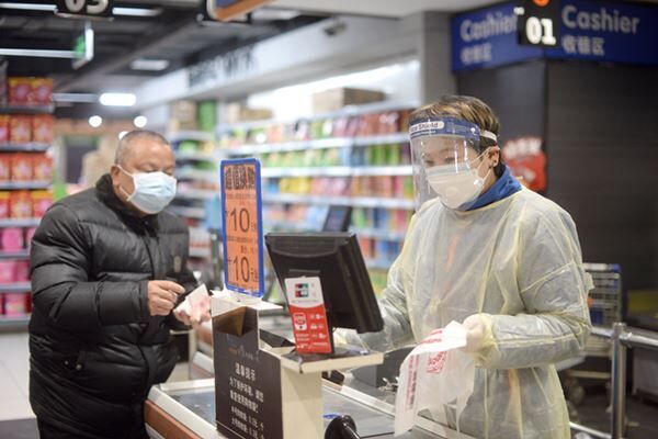 防護服を着用する中国のスーパー（写真：時事通信）