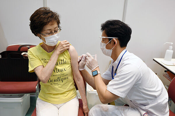 コロナワクチン接種を受ける女性（写真：時事通信）
