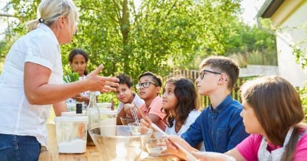 サマーキャンプで料理を教わる子どもたち