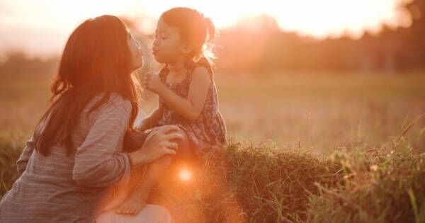 夕日をバックに、綿帽子を飛ばす母子