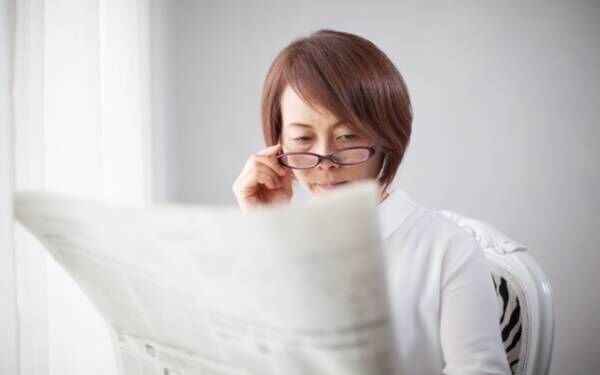 眼鏡を下ろして新聞を読む女性