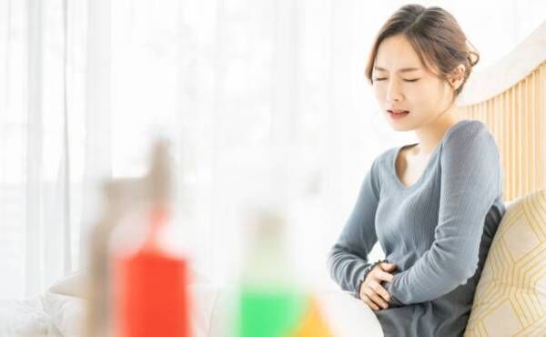下腹部を抑えて生理痛を耐える女性のイメージ