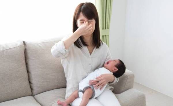 赤ちゃんを抱っこしながら目頭を揉む女性のイメージ