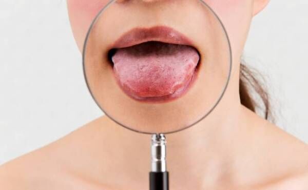 虫眼鏡と舌をだす女性の口元のイメージ