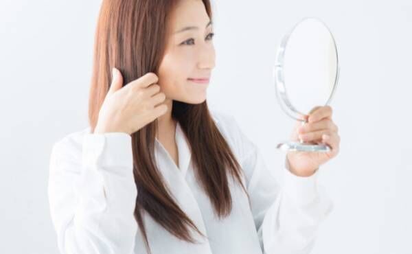 鏡で髪をチェックする女性
