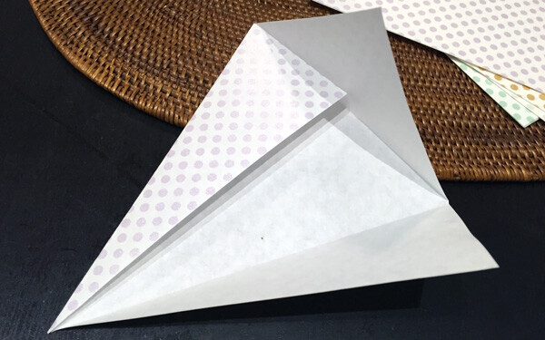 折り紙を三角に折り、テープやのりで折り目をとめる