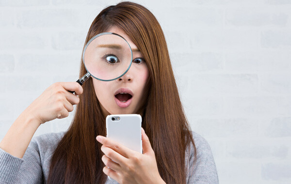 スマートフォンを虫眼鏡で見る女性
