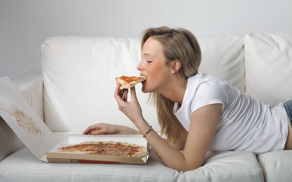 寝ころんでピザを食べる女性