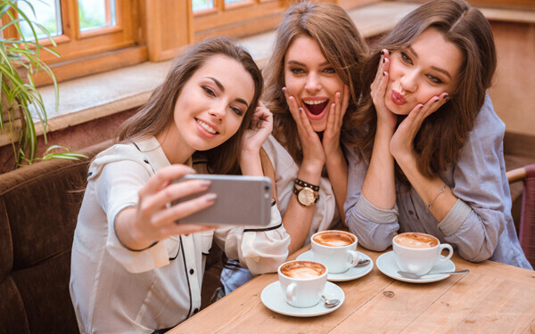 スマートフォンのカメラで、写真を撮っている三人の女性