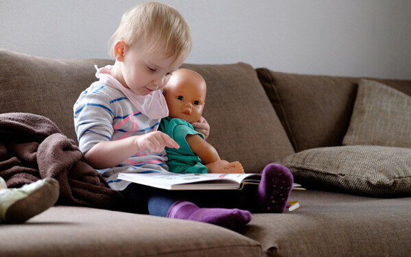 人形を抱え、絵本を読む少女