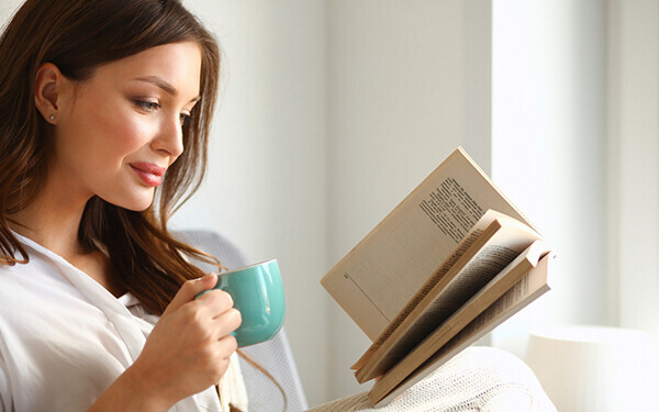 お茶の飲みながら本を読む女性