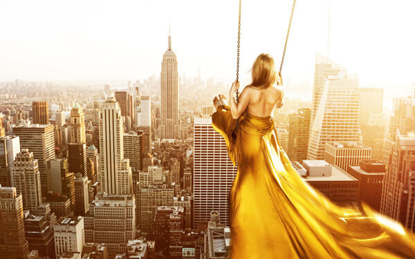 ニューヨークの上でブランコに乗っている女性