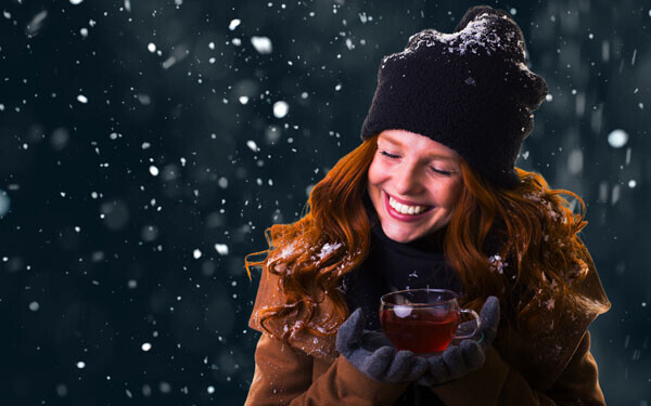 雪が降る中、紅茶を手に持つ女性