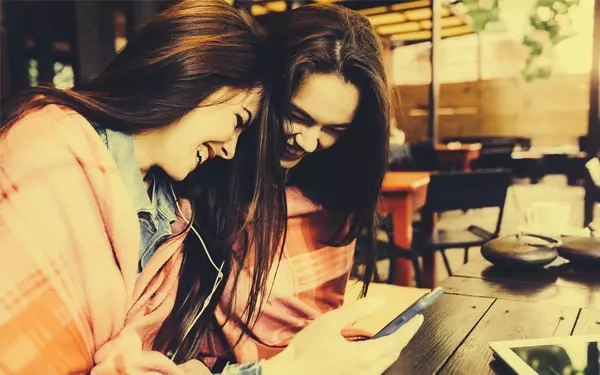 iPhoneを見ながら笑いあう2人の女性