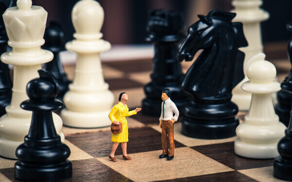チェス盤の上に立っているミニチュアの人間.男女関係