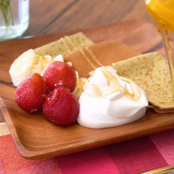 お皿に盛った、コストコ「平飼いたまごとカリフラワーパウダーのクレープ」とカットしたバナナといちごのアップ